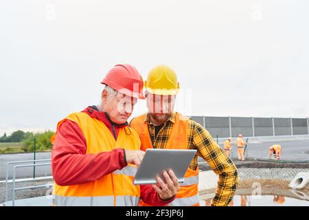 Construction manager and construction worker on the construction site of road construction with tablet computer Stock Photo