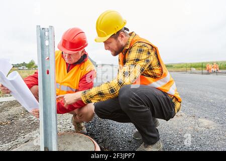 Construction workers team controls guardrails construction on the road construction site Stock Photo