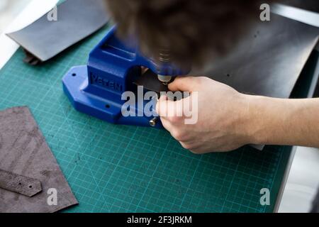 Artisan using hand press for setting snaps in leather for makes a wallet. Hand Pressure Snap Pressing Machine is using by craftsman in leather Stock Photo
