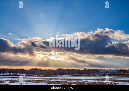 Sunset over the snowy field with sunrays Stock Photo