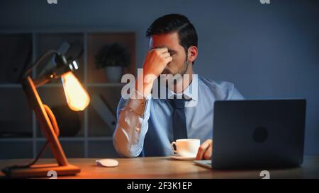 tired businessman touching eyes while working late in office Stock Photo