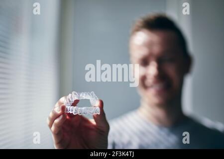 Smiling young man holding trays for teeth whitening. Themes dental health, care and beauty. Stock Photo
