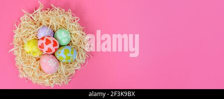Set with colorful Easter eggs in the nest on pink background, banner design. Ornaments drawn by a child. Space for adding text. Childhood, art, drawin Stock Photo