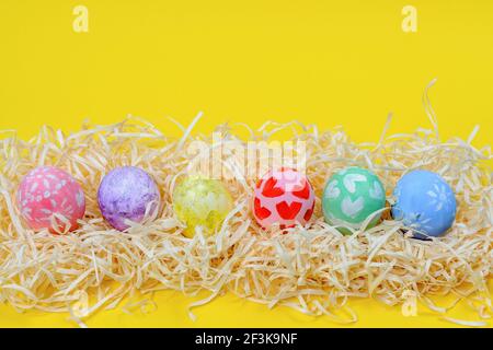 Creative layout. Easter paint colorful eggs various pattern handmade. Row of Easter eggs on paper shavings Stock Photo