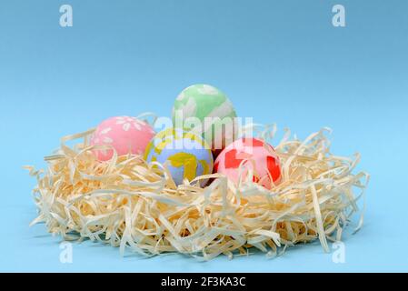 Children decorate colorful Easter eggs. Handmade nest with multi-colored eggs on a blue background. Easter, family, holiday and child concept. Stock Photo