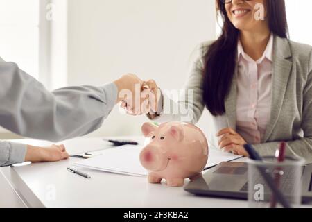 Happy loan broker or bank manager making a deal and shaking hands with her client Stock Photo