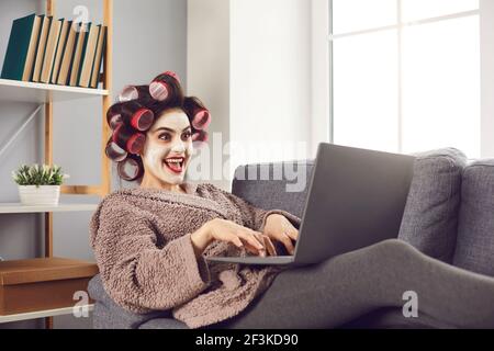 Funny crazy cheerful woman sitting on sofa and working online Stock Photo