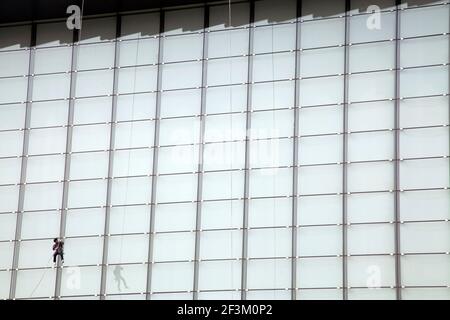 Construction worker hangs suspended while installing window panes on a skyscraper in Shanghai, China Stock Photo
