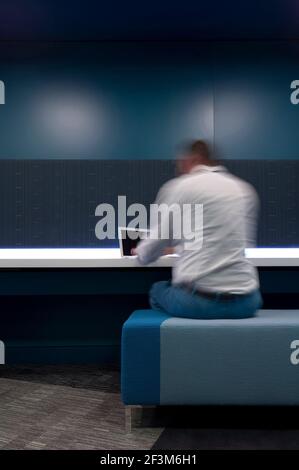 Man sitting working on laptop in interior working space, UK Stock Photo