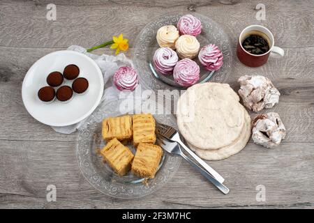 Table with various cookies, tarts, cakes and cup of coffee. Close up, top view. Stock Photo