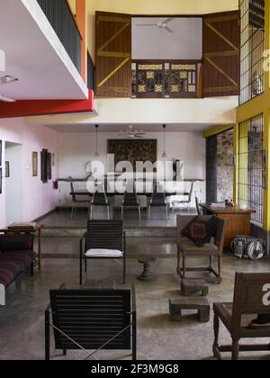 Open plan living and dining area with table and chairs underneath upper level of residential home, Sri Lanka