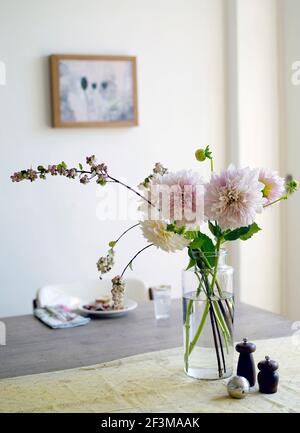 Cut flowers in glass vase on table next to salt and pepper pot in American residential home. Stock Photo