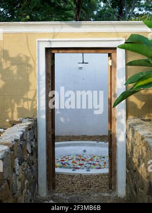 Doorway in wall, leading to outside circular bath and shower in garden of villa, Sri Lanka Stock Photo