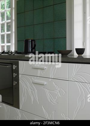 Kettle on hob with white floral patterned fitted units in kitchen of residential home, Denmark Stock Photo