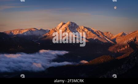 Sunrise at Pedraforca and Alt Berguedà region with Full Moon, viewed from Coll de Pal viewpoint (Berguedà, Catalonia, Spain, Pyrenees) Stock Photo