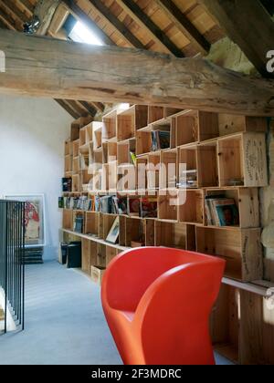 Stacked wooden wine crate storage in interior wooden beamed roof space with artwork, books and vinyl in residential house, France. Stock Photo