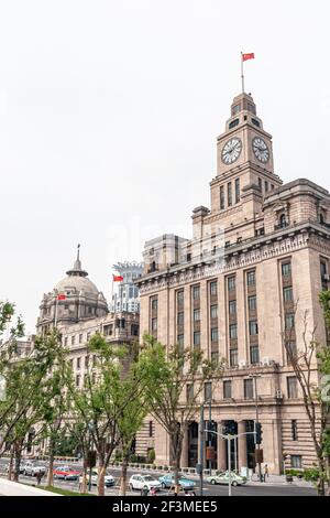 Shanghai, China - May 4, 2010: Customs House with clock tower and domed HSBC building along Bund under silver sky. Cars and pedestrians on street in f Stock Photo