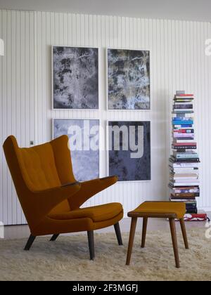 Vintage armchair and footstool with stack of books in California home, USA. Stock Photo