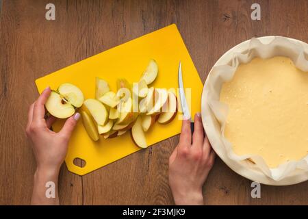 The hostess at home is preparing apple charlotte in the kitchen. puts ingredients on apple pie Stock Photo
