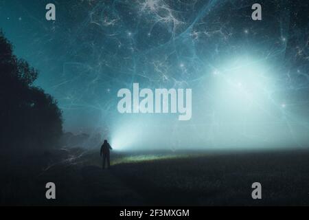 A science fiction concept of a man standing in a spooky field in the countryside, holding a torch. With apocalyptic clouds of energy glowing in the sk Stock Photo