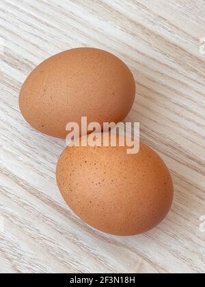 Brown eggs. Top view of two raw organic chicken eggs on wooden table at kitchen. Stock Photo