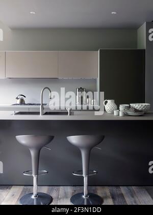 Bar stools at breakfast bar in grey kitchen in USA home Stock Photo