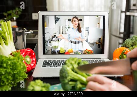 Beautiful happy woman streaming broadcast video blog about tasty and healthy food from home kitchen. Healthy lifestyle and social media. Man watching Stock Photo