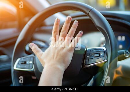 female hand presses the horn on the steering wheel of a modern car. no face Stock Photo