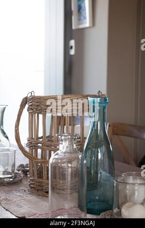 Cane holder with various vases and decanters set on linen clothe on wooden table Stock Photo