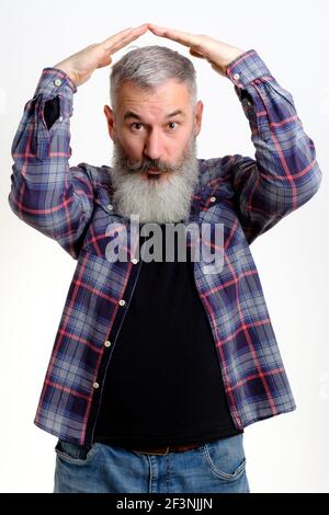 Studio portrait of mature bearded man in casual clothes holding hands above head in roof gesture. I am indoor concept. Isolated on white background. Stock Photo
