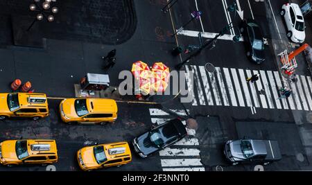 Detail of intersection in Manhattan, with crosswalk, yellow cabs and street food vendor. Stock Photo