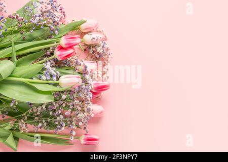 Romantic bouquet of pink tulips and blue gypsophila on pink. Spring greeting card with copy space. Stock Photo