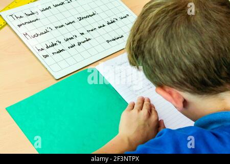 Primary school child writing on a desk during a lesson. Stock Photo