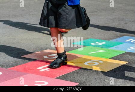 Primary school child playing hopscotch in a school playground during their break from classroom lessons. Stock Photo