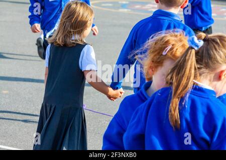 Primary schoolchildren playing in a school playground in a break between classroom lessons. Stock Photo