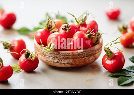Fresh rosehips berries in small wooden bowl Stock Photo