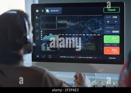 Rear view of programmer looking at computer monitor and working over software with diagrams at office Stock Photo