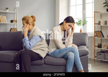 Elderly mother and grown up daughter after quarrel sitting on couch separately Stock Photo