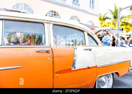 Vintage retro car in Miami Florida with do not touch sign and people in bars restaurants in blurry background on street Stock Photo