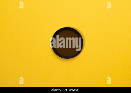 man hand holds a circular polarizer filter, on yellow background. photo accessory Stock Photo