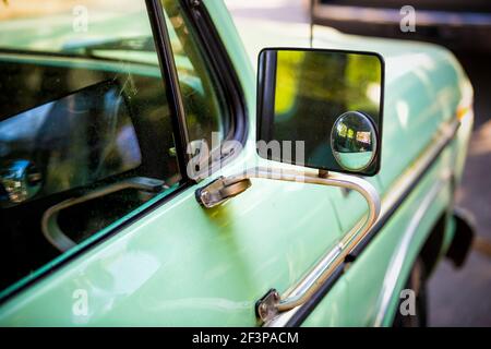 Closeup of green vintage retro style small car parked in Charleston, SC with reflection on side rear view mirror glass Stock Photo