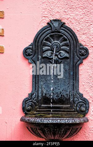 Reykjavik, Iceland colorful painted red building architecture wall with historic water fountain with water running on street downtown Stock Photo