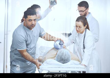 Doctors putting an oxygen mask on patient and pushing gurney stretcher bed in operating room Stock Photo