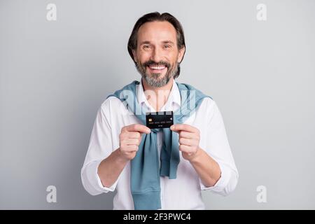 Photo of charming age man wear white shirt sweater shoulders holding bank credit card isolated grey color background Stock Photo