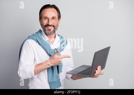 Photo portrait of thoughtful freelancer programmer pointing finger on laptop wearing shirt smiling isolated pastel grey color background Stock Photo