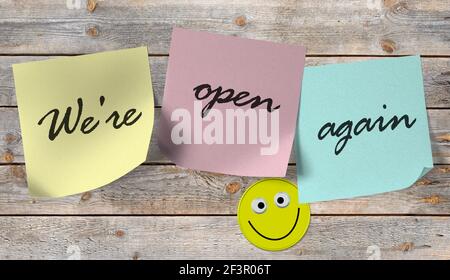 Sticky notes with the text "We're open again" on a wooden wall Stock Photo
