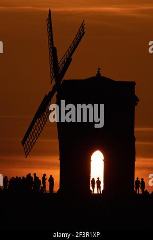 Groups of people watch sunset by Chesterton Windmill in Warwickshire. Picture date: Wednesday March 17, 2021. Stock Photo