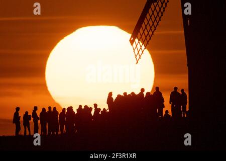 Groups of people watch sunset by Chesterton Windmill in Warwickshire. Picture date: Wednesday March 17, 2021. Stock Photo