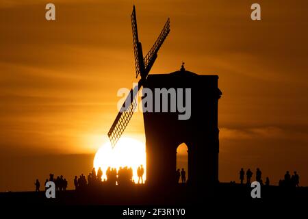 Groups of people watch sunset by Chesterton Windmill in Warwickshire. Picture date: Wednesday March 17, 2021. Stock Photo