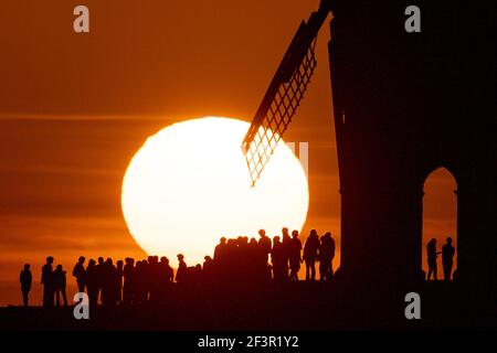 Groups of people watch sunset by Chesterton Windmill in Warwickshire. Picture date: Wednesday March 17, 2021. Stock Photo